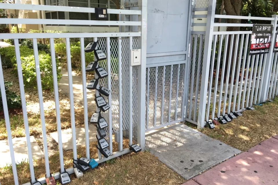 Gate in front of Miami Beach apartment building with many lock boxes for short-term renter access